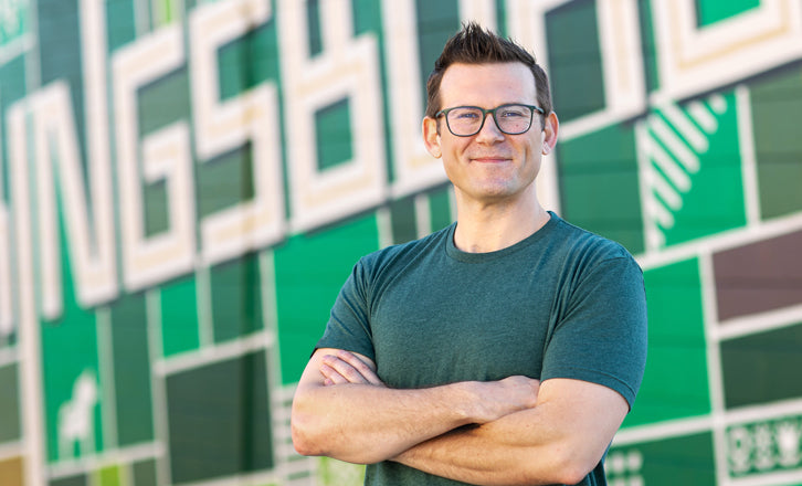 Chris Michel, Graphic Designer, Standing in front of Aerial Kingsburg Mural